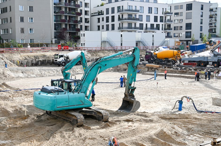 A busy construction site with machinery, workers, and residential buildings.
