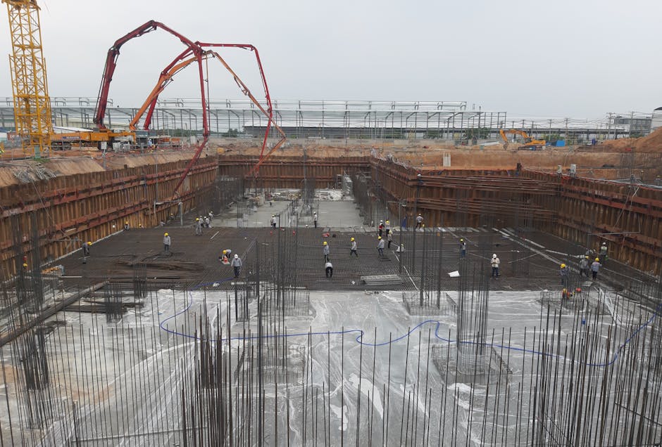 Construction site with workers setting foundation and steel reinforcements.