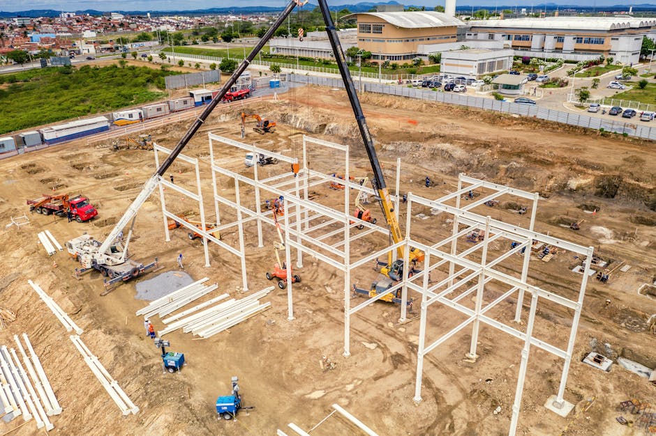 Aerial view of building process with machines and pumpjack near road.
