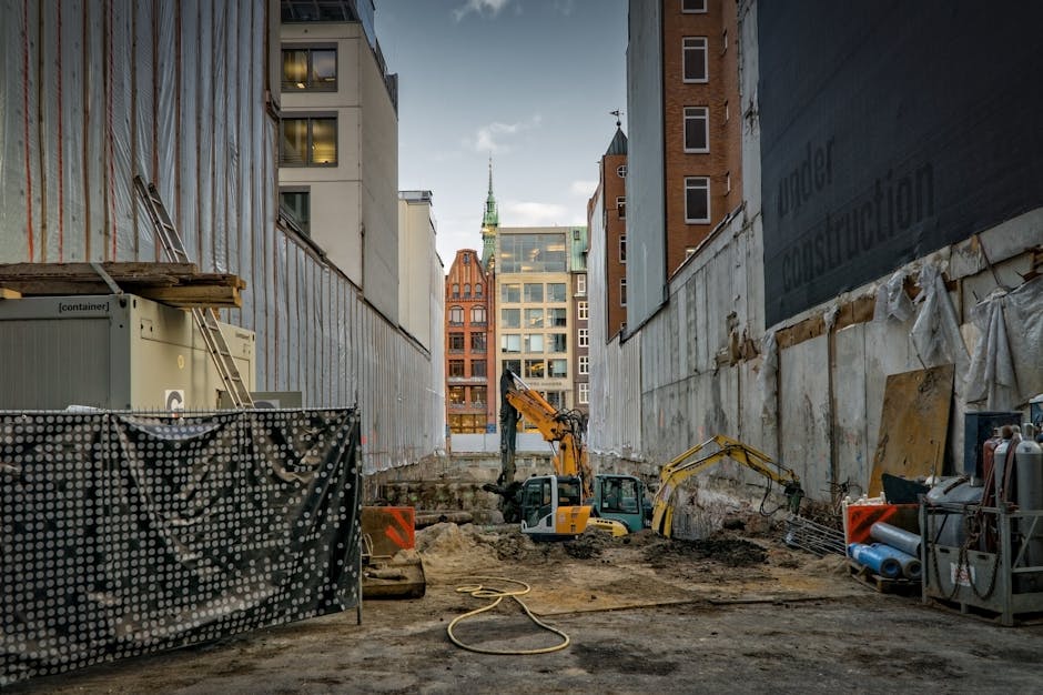 Construction site in an urban area with excavators and scaffolding.