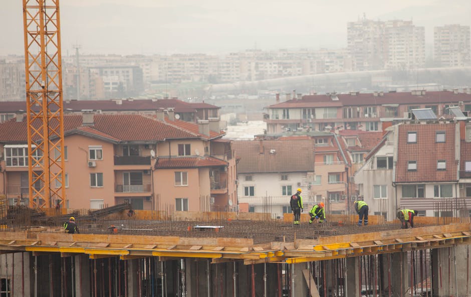 Workers at a city construction site with buildings in the background.